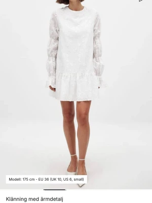 Vit broderad klänning med volang - Jättefin vit klänning med broderade blommor, volangdetaljer och urringning med knyt i ryggen. Klänningen har långa ärmar och är gjord i ett lätt, luftigt material. Perfekt till konfirmation eller skolavslutning. Använd en gång, på konfirmation💕