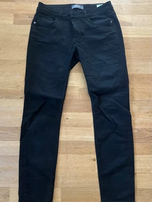 Svarta skinnet jeans - Snygga svarta slim fit jeans från Mos Mosh med klassisk femficksmodell och normal midja. Jeansen har raka ben och är tillverkade i ett stretchigt material för extra komfort. Perfekta för dig som gillar en clean och stilren look.
