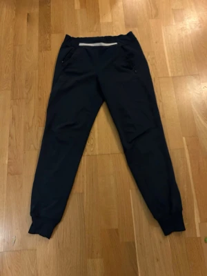 Mörkblå golfbyxor - Svarta golfbyxor med resår i midjan och muddar vid bensluten. Byxorna har två fickor fram och två bakfickor (syns inte så tydligt på bild). Tillverkade i ett mjukt och stretchigt material som passar perfekt för golfspel.