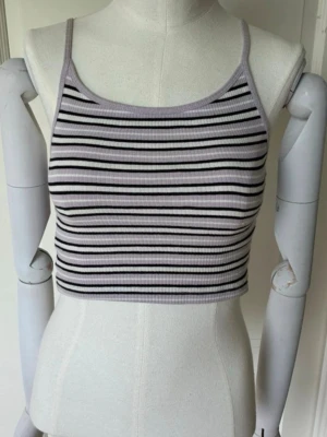 Randig ribbad linnetopp - Säljer en croppad linnetopp med smala axelband. Toppen är ribbad och har ett svart, vitt och lila randigt mönster. Säljer pga att den inte används och kan nog passa lite större storlekar än vad det står eftersom den är lite stretchig💓
