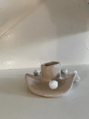 Handgjord beige ljusstake  - Unik handgjord ljusstake i beige  med vågig form och vita dekorativa kulor runt om. Perfekt som en personlig inredningsdetalj och passar för ett smalt ljus. Ger ett kreativt och konstnärligt intryck i rummet.