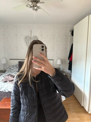 Svart dunjacka med knappar från uniqlo - Snygg svart dunjacka med rund halsringning och knäppning framtill. Jackan har en klassisk, lätt vadderad design som passar perfekt till vår/sensommar. Enkel och stilren modell utan synliga loggor eller detaljer. Den är knappt använd. Nypris 749 