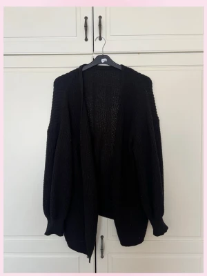 Svart oversized stickad kofta - 💗Mysig svart stickad kofta med oversized passform och långa ärmar. Koftan har ribbstickade muddar och öppen front utan knappar. Perfekt att slänga över en t-shirt eller topp för en avslappnad look.💕bra att ha nu inför lite varmare väder istället för jackan!