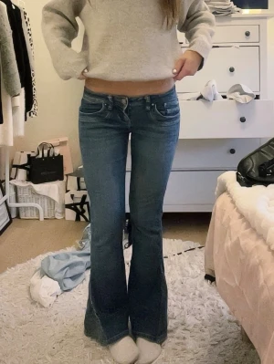 ltb jeans - Säljer ett par blå bootcut jeans med låg midja och klassiska fem fickor. Jeansen har en snygg tvätt och utsvängda ben som ger en retrovibe. Perfekta för dig som gillar en avslappnad men trendig stil. Materialet är denim i bomull.
