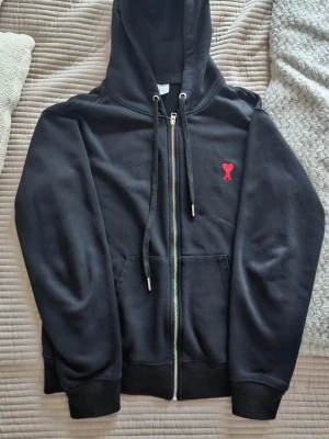 Svart zip up hoodie från Ami Paris - Snygg svart hoodie från Ami Alexandre Mattiussi med dragkedja, huva och dragsnören. Hoodien har fickor framtill och ribbade muddar. Skriv gärna vid funderingar. Ni förstår varför priset är som det är. Sitter som storlek S-M. Skicka gärna bud.😁