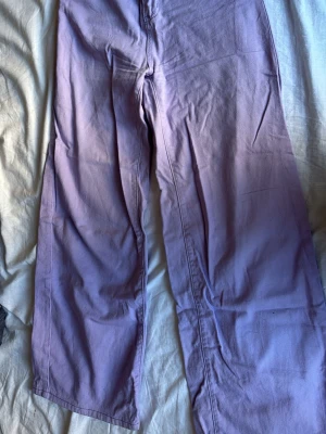 Ljuslila raka jeans - Säljer ett par ljuslila jeans med rak passform och hög midja. Jeansen har klassisk femficksdesign och är tillverkade i ett mjukt bomullstyg. Perfekta för dig som vill addera lite färg till din outfit!