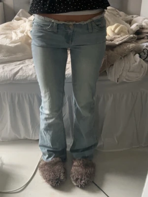 Ljusblå bootcut jeans med låg midja - Säljer ett par ljusblå bootcut jeans med låg midja och klassisk femficksdesign. Jeansen har en lätt tvättad look och stängs med dragkedja och knapp. Perfekta för dig som gillar en avslappnad och trendig stil.