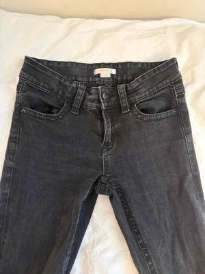 Svarta jeans från Gina Tricot - Snygga svarta jeans från Gina Tricot med klassisk femficksmodell och bootcut ben. Jeansen har fickor bak med detaljer och knappar ⭐️
