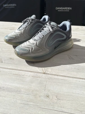 Nike Air Max 720 grå sneakers - Nike Air Max 720 sneakers i grå nyanser med futuristisk design och vågiga detaljer. Skorna har en hög synlig luftbubbelsula och är tillverkade i syntetmaterial och mesh för en sportig look. Klassisk Nike-logga på sidan och snörning framtill.