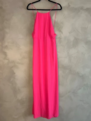 NLY Eve rosa maxiklänning strappy rygg S 36 fest balklänning - Superfin långklänning från NLY Eve i stark rosa färg. Luftig och flowy modell med tunna axelband och öppen rygg – perfekt till fest, sommar eller event.  Storlek: 36 (XS/S) Material: Polyester  Väldigt smickrande passform och faller snyggt på kroppen 