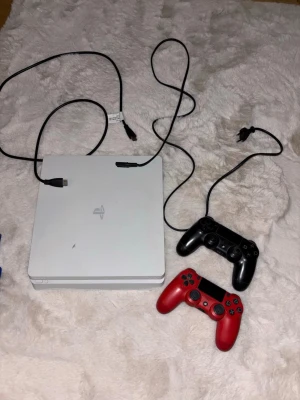 Playstation 4 Slim Vit + 2 kontroller + GTA 5 - Säljer min Playstation 4 Slim i vit färg. Konsolen fungerar perfekt utan problem. Säljer pga att jag uppgraderat till 5an.  Ingår: - 2 handkontroller     • Ena har lite trög X-knapp     • Andra är lite glapp i plasten på sidan och lite slitna spakar (vanligt slitage, fungerar som den ska) - GTA V   - FC 24   - Alla kablar + laddsladd    Perfekt för dig som vill ha en billig konsol med spel direkt 🎮  Pris: 1699 kr (kan diskuteras vid snabb affär)