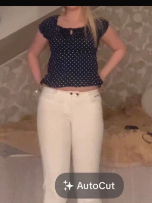 Mörkblå prickig blus med volang - Supersöt mörkblå blus med vita prickar. Blusen har korta ärmar, rund halsringning med liten öppning och knyt framtill. Storlek 40 men passar mig som brukar ha 36💕