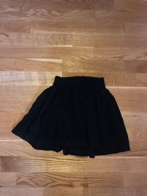 Minikjol luftig volang  - Svart luftig liten kjol från h&m. Storleken är uppskattad då jag inte ser storleksinformation. Supersöt och skön. Mycket stretchig midjeband. Inga synliga tecken på användning