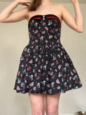 Klänning  - Tänkte sälja den här då jag vill byta klädstil. Jag har gjort ändringar på den! Knapparna där fram bytte jag ut + placerade de nya bredvid resåren istället för ovanpå den för de gamla satt snett. Sydde på spets för hand, så inte jättevackert men det syns inte när den är på. Sydde även fast en tryckknapp ovanför dragkedjan för den åkte upp. Resåren där bak har gått sönder på några ställen men det påverkar inte klänningen förutom att den är mindre stretchig. Klänningen har fickor!