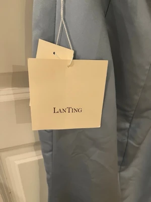 Ljusblå långklänning från LanTing - Ljussblå långklänning från LanTing i ett glansigt material. Klänningen har v-ringad urringningen och en öppen rygg. Klänningen är aldrig använd bara testad en gång. Pris kan diskuteras😊