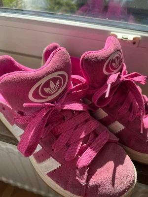 Adidas Campus rosa sneakers - Säljer ett par rosa Adidas Campus sneakers med klassiska vita ränder på sidan och Adidas-logga på tungan. Fläckar finns på skorna men med en bra sprej eller så kan man få bort fläckarna på ett fåtal skrubbar