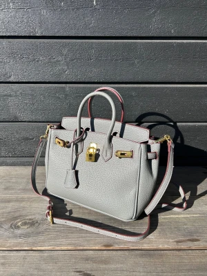 Grå Handväska - Säljer denna jättefina grå "hermessliknand£" väskan i mycket bra skick, nypris 50 000kr+, priset kan diskuteras vid snabb affär så kom gärna med bud!