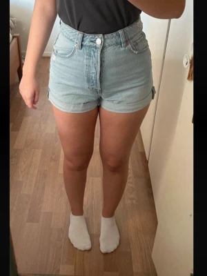 Jeansshorts - Ljusblåa jeansshorts med hög midja. Från Stradivarius i mycket fint skick. Två framfickor och två bakfickor. Material: Bomull