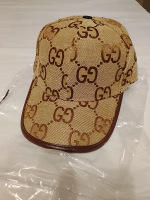 HELT NY GUCCI-KEPS från senaste modellen - Säljer en helt ny Gucci-keps från senaste kollektionen. Kepsen är helt oanvänd och i nyskick, vilket tydligt framgår av bilderna. Perfekt accessoar för dig som vill ha en stilren och exklusiv look.