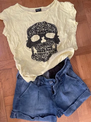 Blå denimshorts med uppvik+Rut med Fketa Gil T-shirt  - Säljer ett par klassiska blå denimshorts med uppvikta ben och knappstängning. Shortsen har fickor fram och bak och är perfekta för en avslappnad och cool stil. Passar dig som gillar jeansmaterial och vill ha något enkelt men snyggt.   +Rut med flera T-shirt i gult med svart 