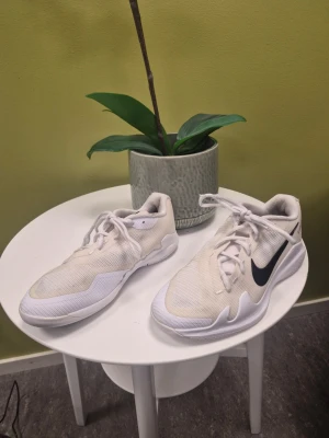 Nike Vapor Pro Tennisskor Vita Storlek 38.5 - Snygga vita Nike sneakers med svart swoosh på sidan. Skorna har en låg profil och är tillverkade i mesh och syntetmaterial för bra ventilation och komfort. Perfekta för dig som gillar sportig stil och vill ha ett par lätta och bekväma sneakers.