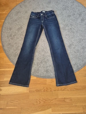 Mörkblå bootcut jeans med kontrastsömmar - Snygga mörkblå bootcut jeans med coola fickor från gina tricot!!! Dessa är jätte sköna och har använt ett par gånger men är INTE slitna alls faktiskt! De är I mjukt material och är I storlek 164! Men om du vill att de ska sitta tajt så bör du vara Xs -S. 