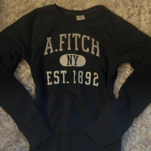 Abercrombie & Fitch sweatshirt - Svart sweatshirt från Abercrombie & Fitch med tryck i vitt framtill: 'A. Fitch NY EST. 1892'. Tröjan har rund halsringning och långa ärmar. Perfekt för en chill och avslappnad stil. (Den finns fortfarande kvar att köpa, även om datumet står att det har gått ganska länge 💕💕💕)