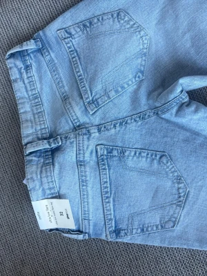 Los waist Ljusblå flare jeans från gina Tricot  - Säljer ett par ljusblå jeans från gina med utsvängda ben och klassiska fem fickor. Jeansen har en snygg tvättad look, låg midja och silverfärgad knapp. Tillverkade i bomull för en skön och avslappnad stil. Perfekta till vardagsoutfits!