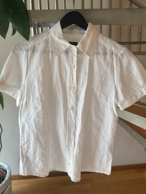 Vit Gant blus  - Snygg vit Gant blus. Den är figursydd i armarna och tyget har ett rutigt mönster. Funkar till både stranden men också till finare tillfällen. Klassisk och stilren
