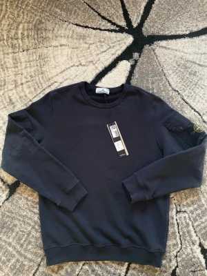 Stone Island Tröja - En helt ny stone Island tröja med taggarna kvar. Tröjan var köpt på NK i Göteborg och blev i fel storlek. Eftersom jag bor långt från Göteborg kan jag ej byta den. Nypris 3799kr. Mitt pris är 2799kr. Tröjan är äkta och seriösa köpare kan be om clg kod så skickas den om man själv skulle vilja kolla äkthet. Oseriösa ignoreras. Aldrig använd! Eller tvättad.