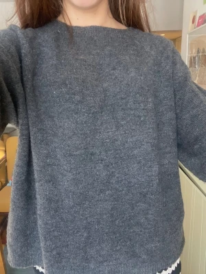 Mörkgrå stickad t-shirt - Mysig grå stickad tröja med rak och avslappnad passform. Tröjan har rund halsringning och kortärmade armar. Perfekt för lager på lager och enkel att matcha till olika outfits.