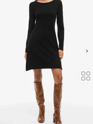 Svart stickad klänning Vila - Svart stickad klänning från Vila med lång ärm och rund halsringning. Modellen är enkel och klassisk, med en rak passform som slutar ovanför knät. 