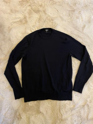 Mörkblå  tröja från Uniqlo - En stilren mörkblå stickad tröja från Uniqlo med rund halsringning och långa ärmar.  Perfekt basplagg i garderoben och enkel att matcha. Hör av dig vid minsta lilla fundering!