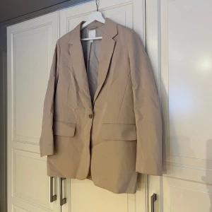 Beige kavaj från H&M - Stilren beige kavaj från H&M. Sparsamt använd.
