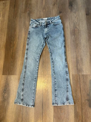 Blå bootcut jeans med broderade fickor - Säljer ett par ljusblå bootcut jeans med snygga broderade detaljer på bakfickorna. Jeansen har klassisk femficksmodell, normal midja och är tillverkade i denim. Perfekta för dig som gillar en avslappnad men trendig stil. Helt nya inga defekter alls!💓🌸