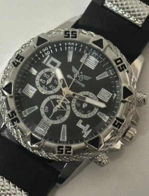 Svart och silver klocka från Zhowe - klocka från Zhowe med svart urtavla, silverfärgade detaljer. Boetten är robust med markerade siffror och sportig känsla. Armbandet är svart med silvriga metallinslag och är justerbart. Har används väldigt sällan.