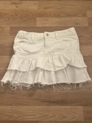 Vit volangkjol med råa kanter - Säljer en vit kortkjol med volanger och råa, fransiga kanter. Trendig, och perfekt nu till sommaren som gör bena ännu brunare! 🤩 Strl XS men passar nog S också, lappen är avklippt så vet inte exakta storleken men passar dem som har xs eller small. 