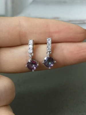 Silverörhängen med lila sten - Snygga örhängen i silver med gnistrande vita stenar upptill och en rund, lila sten som hänger ned. Klassisk och elegant design med metallinfattning och glittrande detaljer. Perfekt för dig som gillar stilrena accessoarer med lite färg.