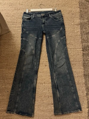 Blå bootcut jeans med kontrastsömmar - Säljer ett par blå bootcut jeans med coola sömmar. 