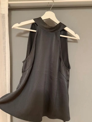 Mörkgrå ärmlös omlottopp - Så snygg mörkgrå halternecktopp från samsøe samsøe. Älskar verkligen denna modellen av topp och har den i flera färger, men det har blivit lite för många… Säljer därav denna som är precis som ny, inga defekter (nypris 1200 kr). Vill tipsa om att den både går att styla upp och ned! Perfekt till ett par jeans men oslagbar till fest med kostymbyxor. 🥰💗