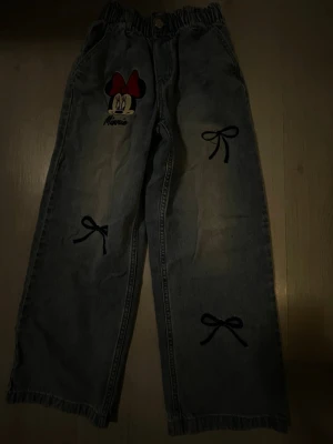 Barn Jeans byxor mickey mouse   - Säljer ett par ljusblå, jeans som e mickey mouse.