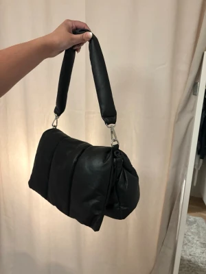 Väska - Säljer en svart puffig axelväska, från nelly, väldigt rymlig. 50kr + frakt 