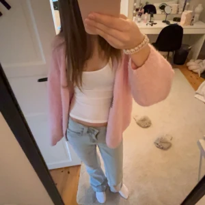 Ljusrosa fluffig kofta från Lindex - Mysig o populär ljusrosa kofta från Lindex i fluffigt material. Koftan har en öppen front utan knappar och långa ärmar. Perfekt för att lägga till en söt touch till din outfit och superbekväm att bära över ett linne eller t-shirt. Skicka gärna om ni har frågor!