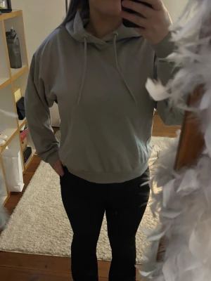 Ljusgrå hoodie med huva - En stilren ljusgrå hoodie med huva och dragsnören. Hoodien har en avslappnad passform, ribbade muddar vid ärmar och midja samt är tillverkad i mjukt material. Perfekt för en chill och enkel look.