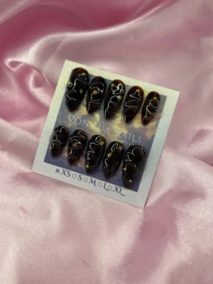 DarkSyrup (XS);Medium Almond - Snygga press-on naglar i brun sköldpaddsmönstrad design med vita abstrakta linjer och små gulddetaljer. Formen är almond och naglarna har en glansig finish. Perfekt för dig som vill ha en unik och trendig look.