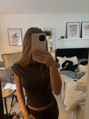 Brun croppad topp med kort ärm - Snygg brun croppad topp med korta ärmar och rund hals. Enkel och stilren design som passar perfekt till jeans eller kjol. Mjuk och stretchig känsla för en bekväm passform. Aldrig använd!