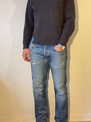 Diesel vintage jeans - Säljer ett par blå jeans med raka ben och snygga slitningar på låren och knäna. Jeansen har klassisk femficksmodell och normal midja. Perfekta för en avslappnad och trendig stil. Materialet är denim i bomull.