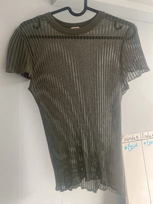 Ribbad grön topp ZARA - Snygg ribbad topp i transparent grönt material med korta ärmar och rund hals. Säls då den inte kommer till andvändning. Toppen har ett litet hål där fram men syns knappt 