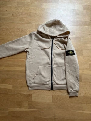 Beige Stone Island Hoodie - Sitter riktigt skönt, endast använd fåtal gånger. Skriv gärna vid övriga frågor!