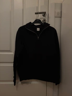 Svart halvzip tröja från Zara - Snygg svart tröja från Zara med halvzip och hög krage. Perfekt för lager på lager och enkel att matcha med olika outfits. Tröjan har långa ärmar och en stilren look som passar till det mesta.